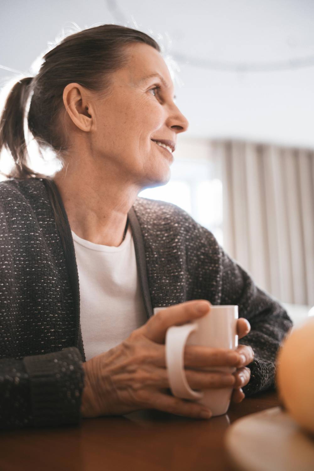 a woman sitting at a table holding a cup