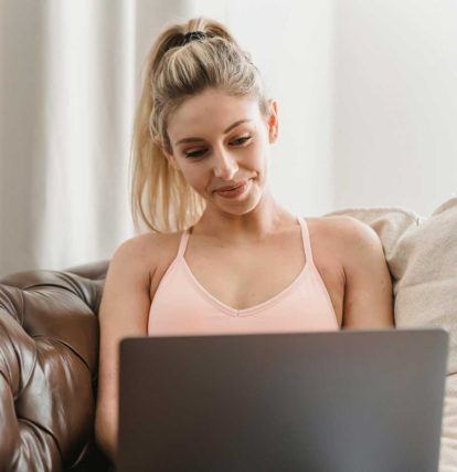 a woman sitting on a leather couch working on a laptop