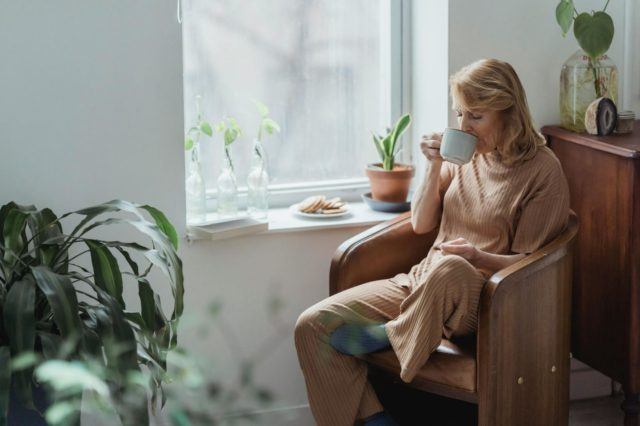 Woman sitting by a window and drinking a cup of tea